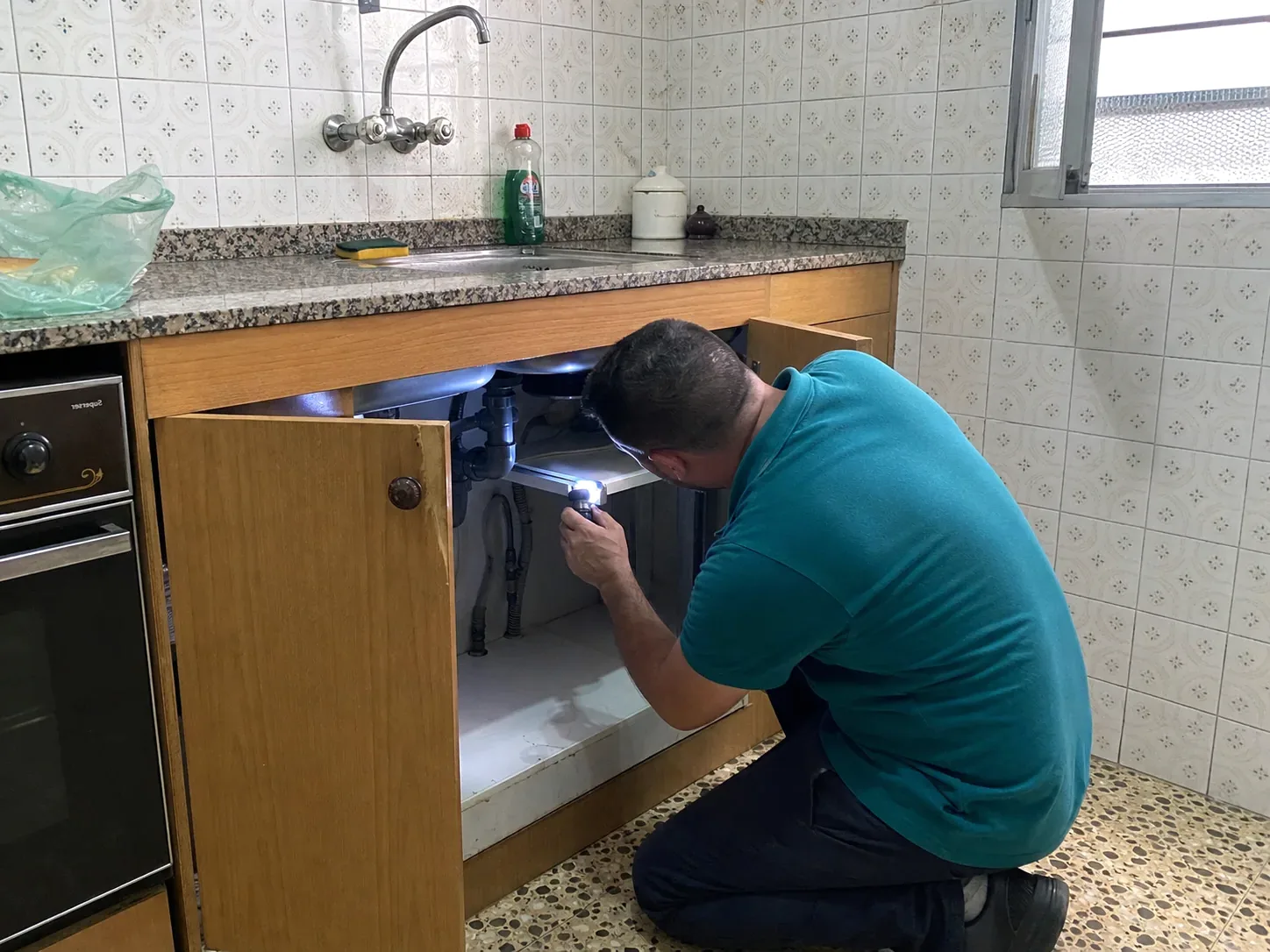 Técnico de ParetsControl inspeccionando una cocina con linterna